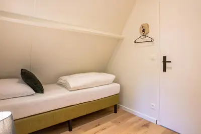 a small room with a bed with a cross on the wall at Boshuisje Rekem - Kitoko in Lanaken