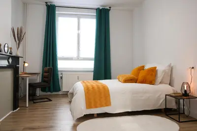 a bedroom with a bed with green curtains and a window at Cozy Home Liege in Liège
