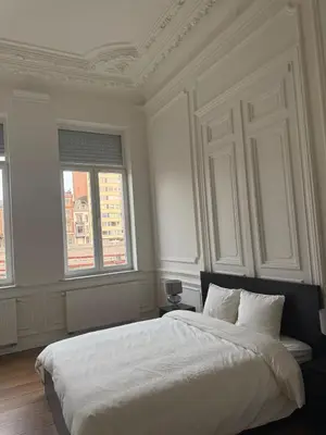 a bedroom with a large white bed with two windows at Luxury Riverfront Apartment near La Meuse in Liège