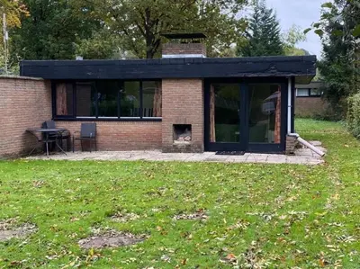 a small house with a fireplace in a yard at Bungalow in Sonnevijver - Hoge kempen in Lanaken