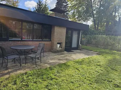 a patio with a table and chairs in a yard at Bungalow in Sonnevijver - Hoge kempen in Lanaken