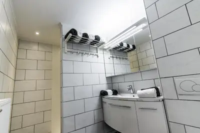 a white tiled bathroom with a sink and a mirror at Vakantiewoningen De Jud in Maasmechelen