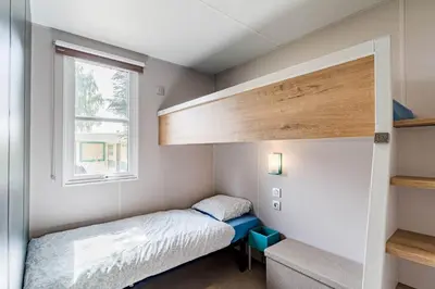 a small bedroom with a bed and a window at Family chalet Kinrooi - Papillon Kinrooi in Kinrooi