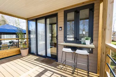 a screened in porch with two stools on a deck at Family chalet Kinrooi - Papillon Kinrooi in Kinrooi