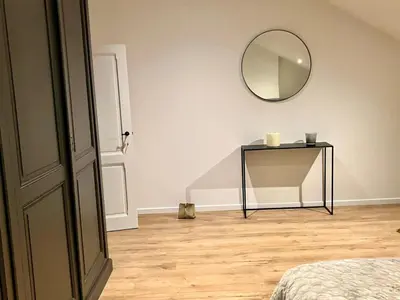 a room with a table with a mirror and a bed at Crossborder Nest - Appartement de standing proche du circuit SPA-FRANCORCHAMPS et des HAUTES-FAGNES in Verviers