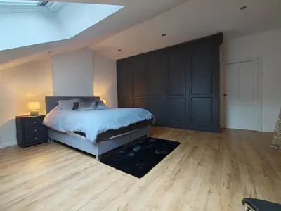 a bedroom with a bed and a wooden floor at Crossborder Nest - Appartement de standing proche du circuit SPA-FRANCORCHAMPS et des HAUTES-FAGNES in Verviers