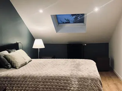 a bedroom with a bed and a flat screen tv at Crossborder Nest - Appartement de standing proche du circuit SPA-FRANCORCHAMPS et des HAUTES-FAGNES in Verviers