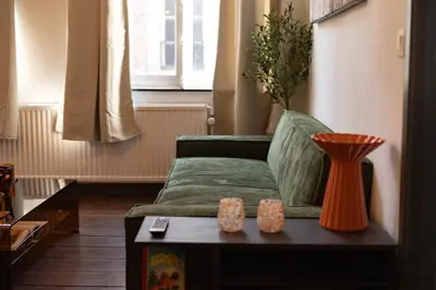 a living room with a green couch and a table at Le cocon chic - Hypercentre, Place du Marché in Liège