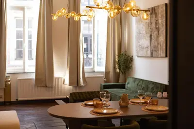 a dining room with a table and a couch at Le cocon chic - Hypercentre, Place du Marché in Liège
