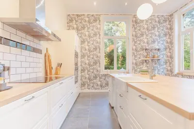a kitchen with white cabinets and a sink and windows at 12P 6B Renovated villa with jacuzzi at Genk in Genk