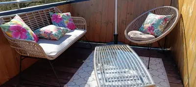 two wicker chairs and a bench on a porch at Tiny House Dreiländereck in Neu-Moresnet
