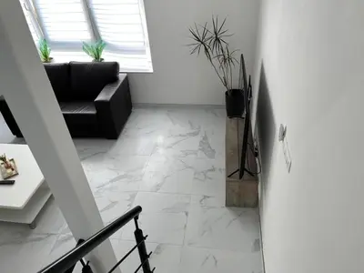 a living room with a black couch and marble floor at DEDIA Guest Home