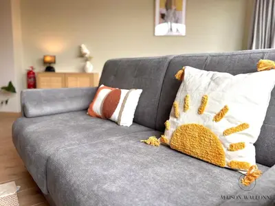 a gray couch with pillows on it in a living room at Le 180 escapade face à la Meuse in Liège