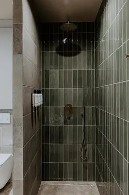 a bathroom with a shower with green tiles at Hangar C gastensuites in Heers