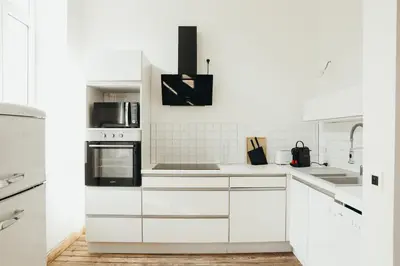 a white kitchen with white cabinets and appliances at Simonis, Parc de la Boverie by WelcHome in Liège