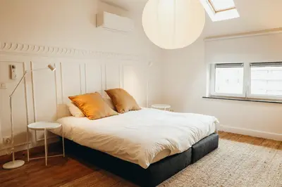 a bedroom with a bed with white sheets and orange pillows at Simonis, Parc de la Boverie by WelcHome in Liège