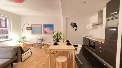 a kitchen and living room with a table in a room at Cozy Neuvice apartment in Liège