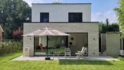 a house with an umbrella and chairs in the yard at Bocca in Hasselt