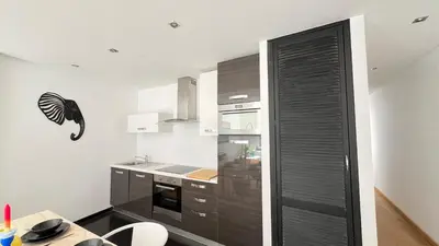 a kitchen with wooden cabinets and a black door at 102 Cozy Neuvice in Liège
