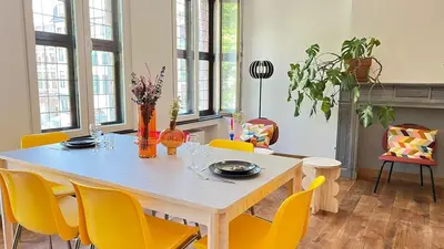 a dining room with a table and yellow chairs at 201 Loft Lumineux en Hyper-Centre in Liège