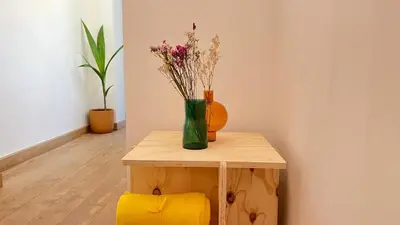 a table with a vase of flowers and a yellow stool at 301 Loft Chic Central in Liège