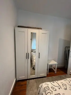 a bedroom with a white cabinet with a mirror at home sweet home in Liège