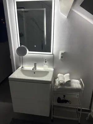 a bathroom with a sink and a mirror and towels at La suite 7 Sauna et jacuzi in Seraing