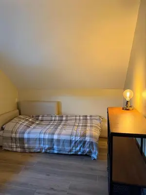 a bedroom with a bed and a table with a lamp at Duplex appartement met 3 slaapkamers in Genk