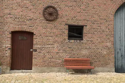 a wooden bench sitting in front of a brick building at Luxe loft in vierkantshoeve in Sint-Truiden