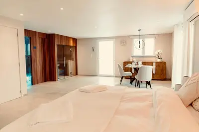 a bedroom with a white bed and a dining room at La Suite Kalys in Thimister