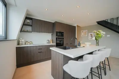 a kitchen with a island with a sink and bar stools at Superbe appartement 2 chambres en centre-ville in Liège