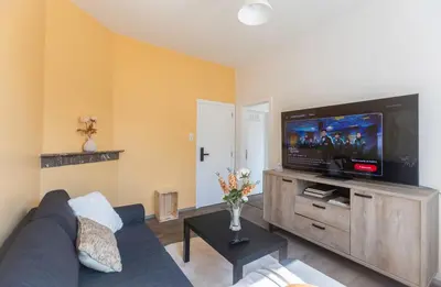 a living room with a blue couch and a flat screen tv at Appartement de luxe Dubai , Chambre, salon et SDB Privés, cuisine partagée in Liège