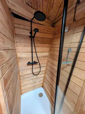 a sauna with a shower in a wooden wall at la pomme de pin Cornesse