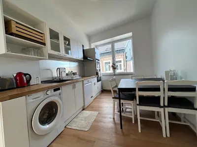 a kitchen with a washing machine and a table with chairs at Chambre New York à Liège Moderne avec salle de bain privée spacieuse, check in autonome, 2eme etage in Liège
