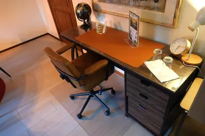 an office with a desk with a chair and a clock at Le Grand Jardin in Dalhem