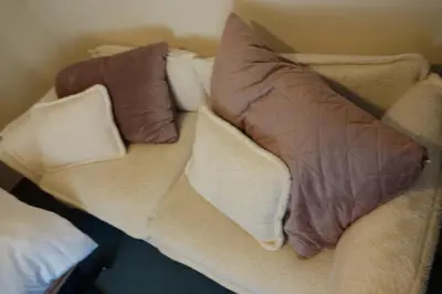 a couch with two pillows on top of it at Le Grand Jardin in Dalhem