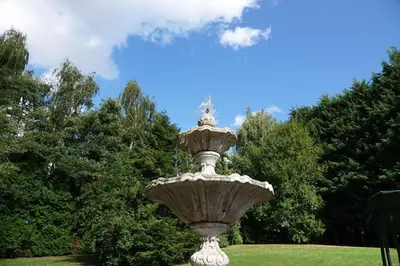 a large stone fountain in a park with trees at Le Grand Jardin in Dalhem