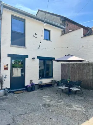 a patio with a table and an umbrella at La maison de MiLy in Bassenge