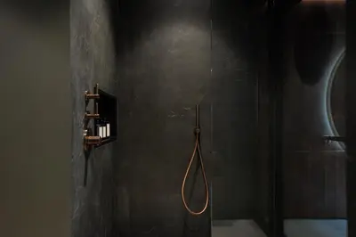 a black bathroom with a shower with a hose at Suite Escape in Hasselt