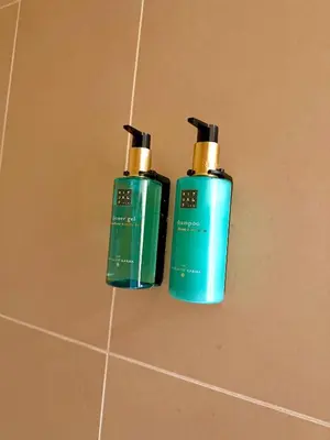 two green bottles ofodorizers sitting on a bathroom floor at Aurora City Apartment in Lommel