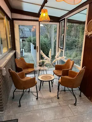 a screened in porch with chairs and tables and a chandelier at Casa Sahara - 8 guests - near nature reserve in Lommel
