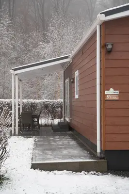 a covered porch of a house with snow on the ground at Camping Natuurlijk Limburg - Chalet 4 in Voeren