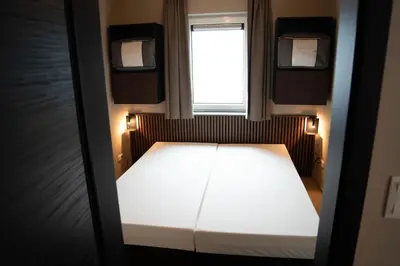 a small bed in a small room with a window at Camping Natuurlijk Limburg - Appartement in Voeren