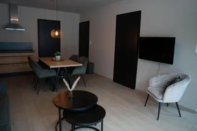 a living room with a table and chairs and a tv at Camping Natuurlijk Limburg - Appartement in Voeren