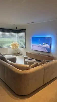 a living room with a large couch and a flat screen tv at Inspire Residence and private Wellness in Tongeren