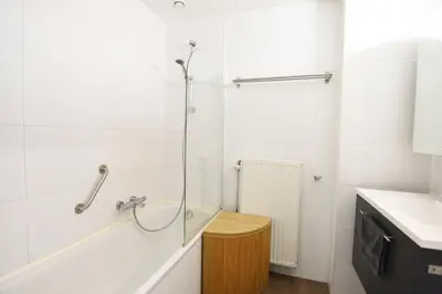 a white bathroom with a tub and a sink at La petite Naimette in Liège