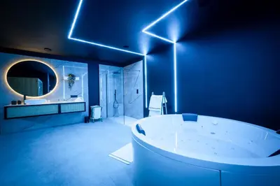 a blue bathroom with a tub and a mirror at Suite Ôna in Bassenge