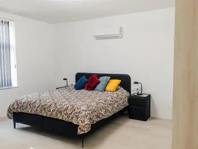 a bedroom with a bed with colorful pillows on it at Le Surdan in Bassenge