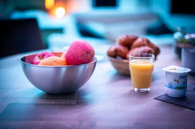 a bowl of fruit on a table with a glass of orange juice at Suite Soma in Bassenge