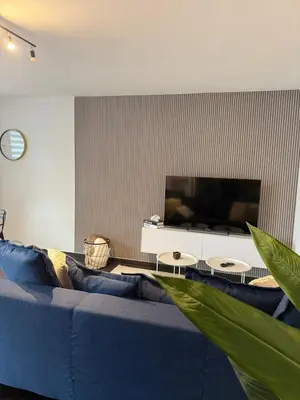 a living room with a blue couch and a flat screen tv at Urban Cocoon in Liège